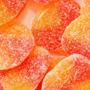 A bunch of orange and red sour fuzzy peach gummies.