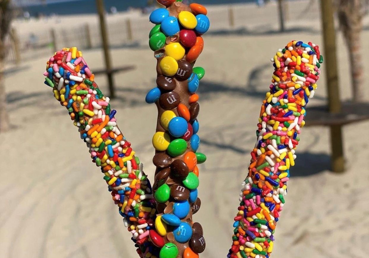 3 assorted topping chocolate covered pretzel rods displayed on the beach at Jenkinson's.